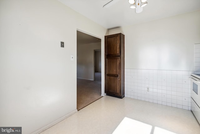 unfurnished room with a wainscoted wall, light floors, and tile walls