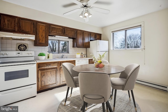 kitchen with under cabinet range hood, a sink, backsplash, white appliances, and light countertops