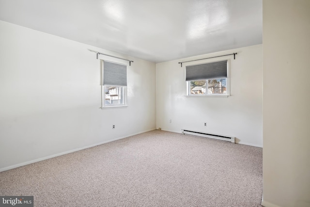 spare room with a baseboard heating unit, baseboards, and carpet