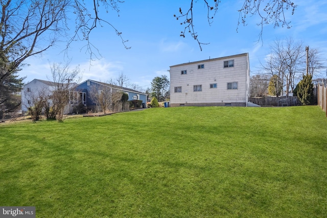 back of property with a lawn and fence