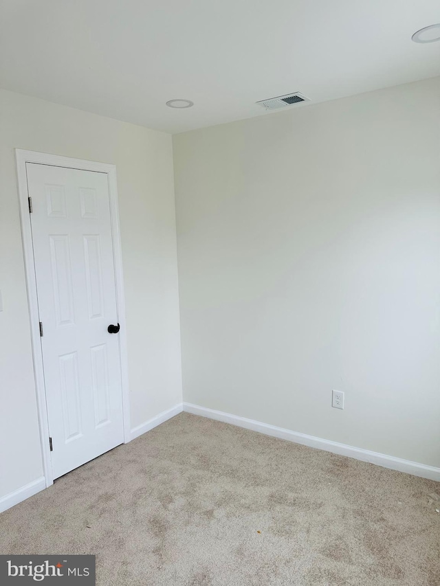 carpeted spare room with visible vents and baseboards