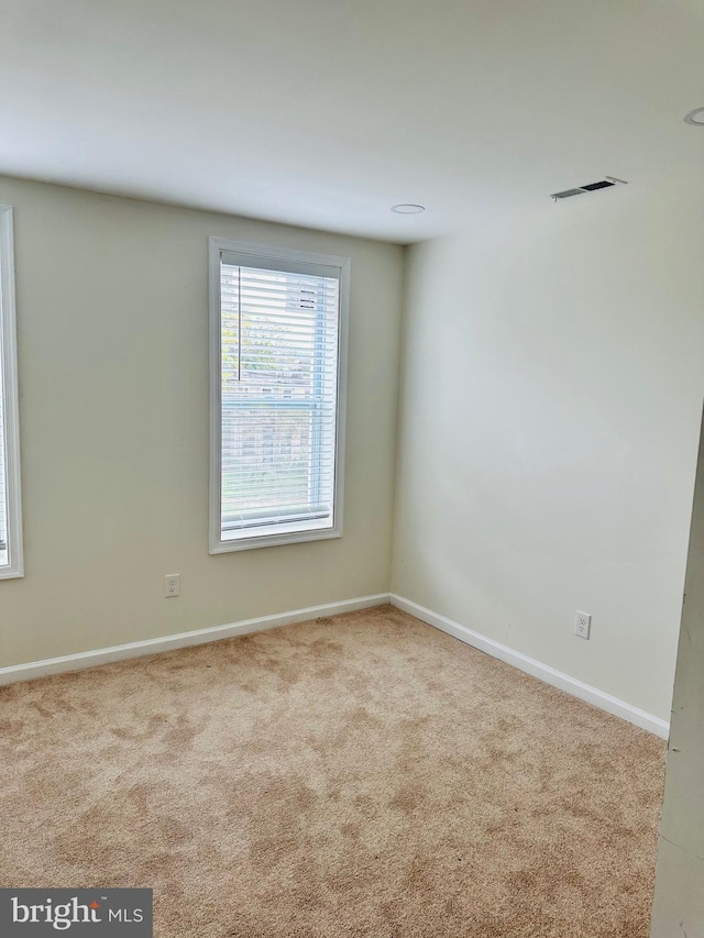 empty room featuring carpet floors, visible vents, and baseboards