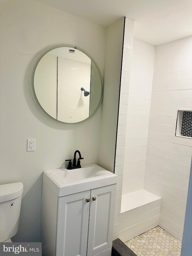 full bath with toilet, tiled shower, and vanity