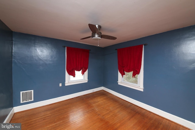 unfurnished room with visible vents, baseboards, and wood finished floors