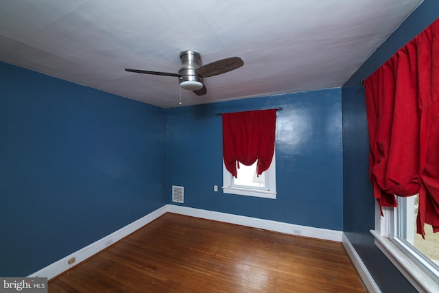 unfurnished room with baseboards, visible vents, ceiling fan, and wood finished floors