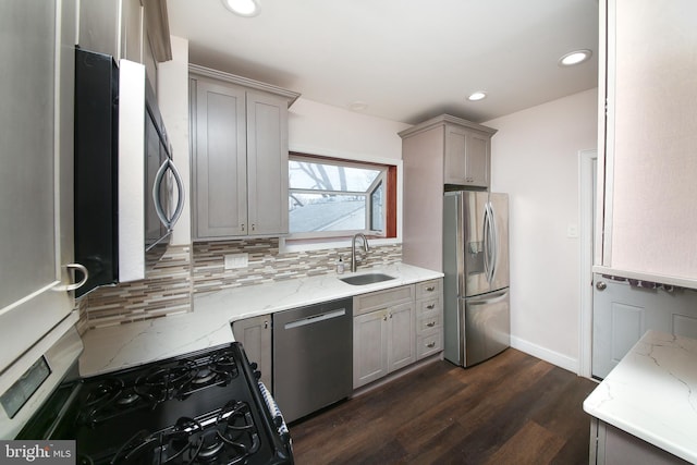 kitchen with dark wood finished floors, stainless steel appliances, backsplash, gray cabinetry, and a sink