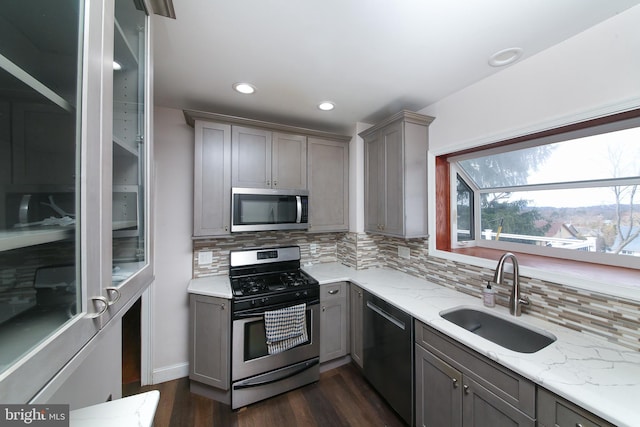 kitchen with stainless steel appliances, gray cabinets, a sink, and decorative backsplash