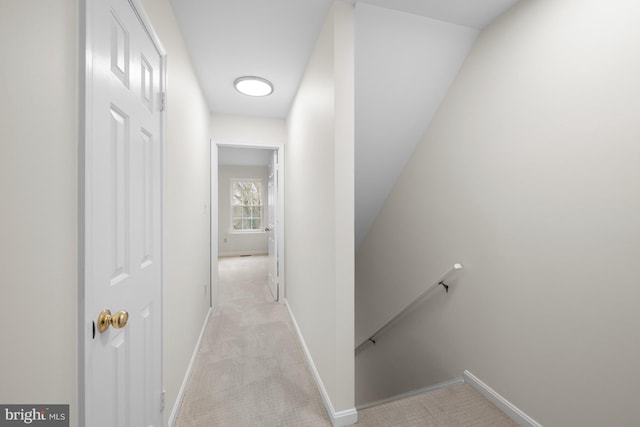 corridor with light carpet, an upstairs landing, and baseboards