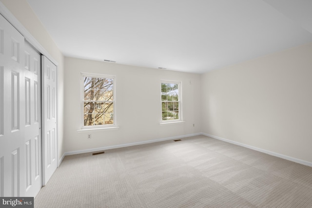 unfurnished bedroom with baseboards, visible vents, and light colored carpet