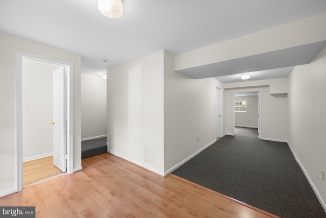 hall with baseboards, visible vents, and wood finished floors