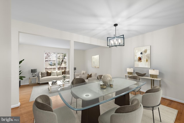 dining space with an inviting chandelier, wood finished floors, and baseboards