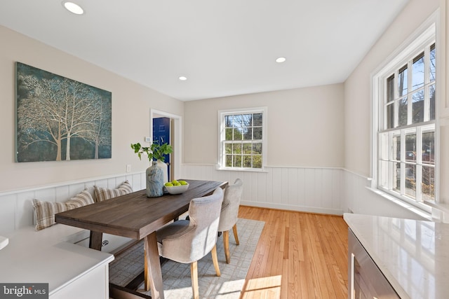 dining room with recessed lighting, a wainscoted wall, and light wood finished floors