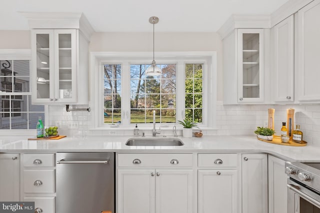 kitchen with appliances with stainless steel finishes, white cabinetry, light countertops, and a sink