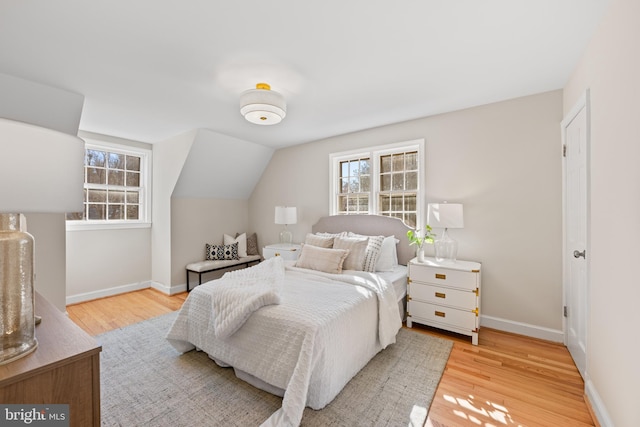 bedroom with light wood finished floors, multiple windows, and baseboards