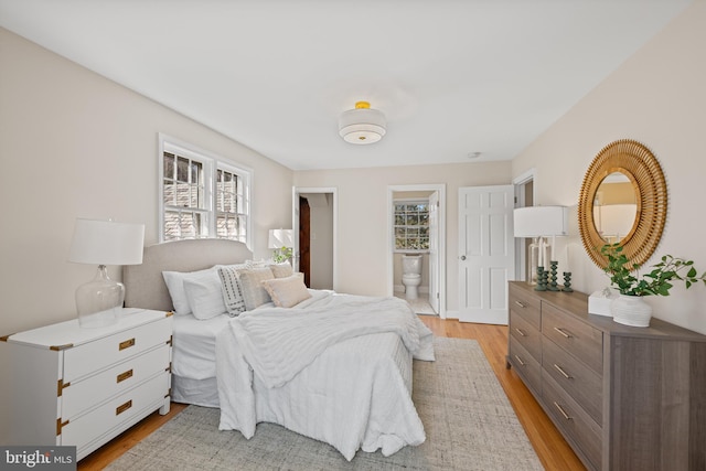 bedroom with multiple windows, light wood-style flooring, and ensuite bathroom