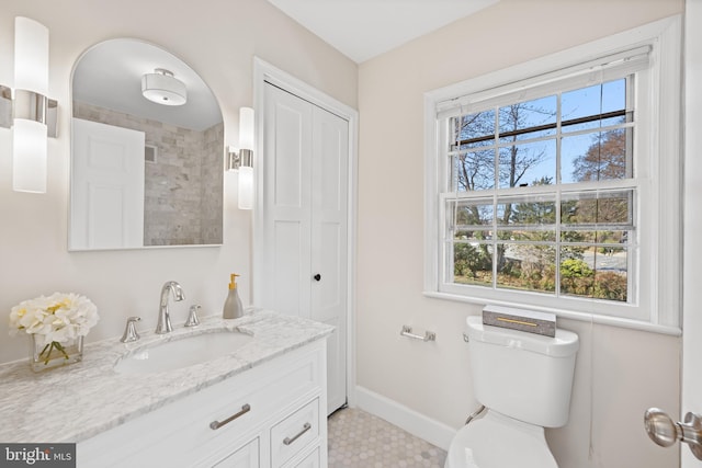 bathroom featuring a wealth of natural light, toilet, vanity, and baseboards