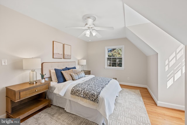 bedroom featuring a ceiling fan, light wood-type flooring, baseboards, and vaulted ceiling