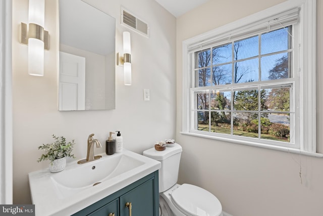 half bathroom featuring visible vents, toilet, and vanity