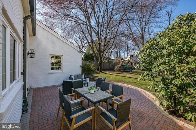 view of patio / terrace with outdoor dining area, fence, outdoor lounge area, and a playground