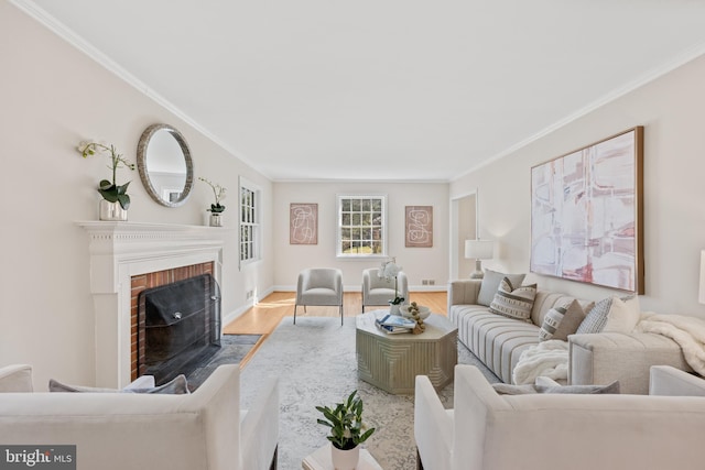 living room with a brick fireplace, crown molding, baseboards, and wood finished floors