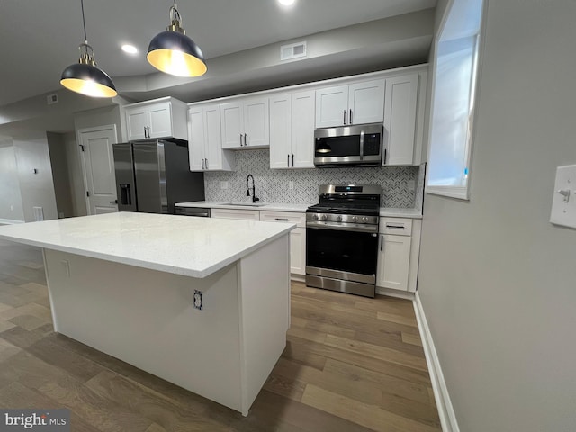 kitchen featuring a center island, visible vents, appliances with stainless steel finishes, a sink, and wood finished floors