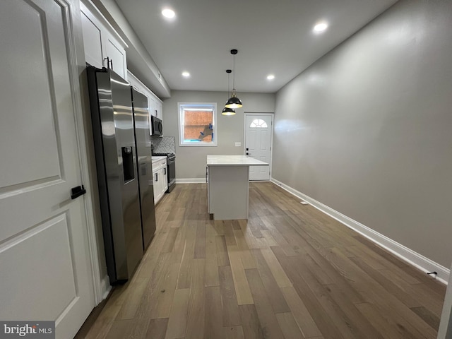 kitchen with white cabinets, stainless steel fridge with ice dispenser, wood finished floors, a center island, and backsplash