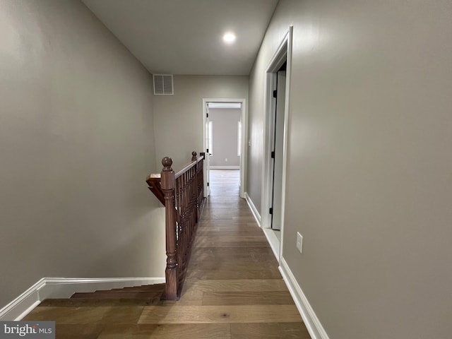 hall featuring baseboards, visible vents, an upstairs landing, and wood finished floors