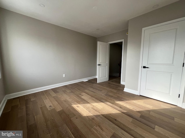 unfurnished bedroom with wood finished floors and baseboards