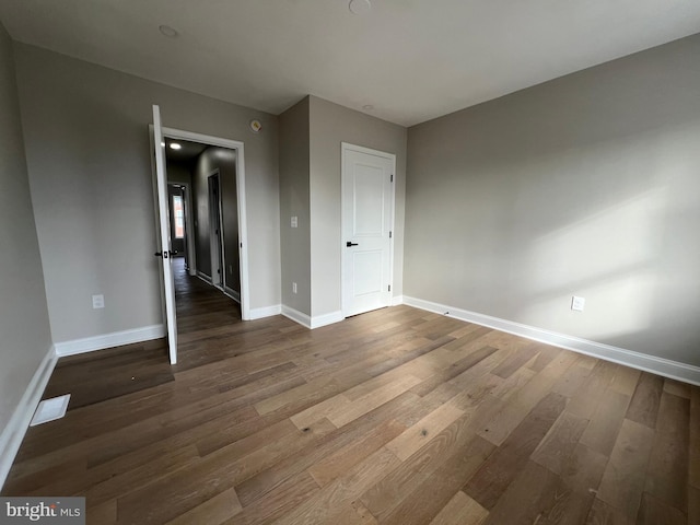 spare room with visible vents, baseboards, and wood finished floors