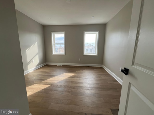 unfurnished room with wood-type flooring and baseboards