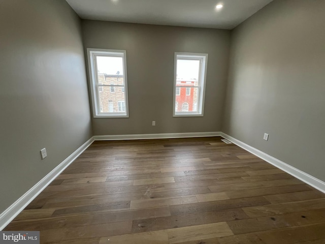 empty room with dark wood-style floors, recessed lighting, a healthy amount of sunlight, and baseboards