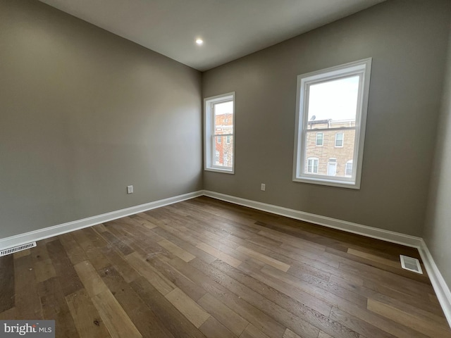 unfurnished room featuring dark wood-type flooring, recessed lighting, visible vents, and baseboards