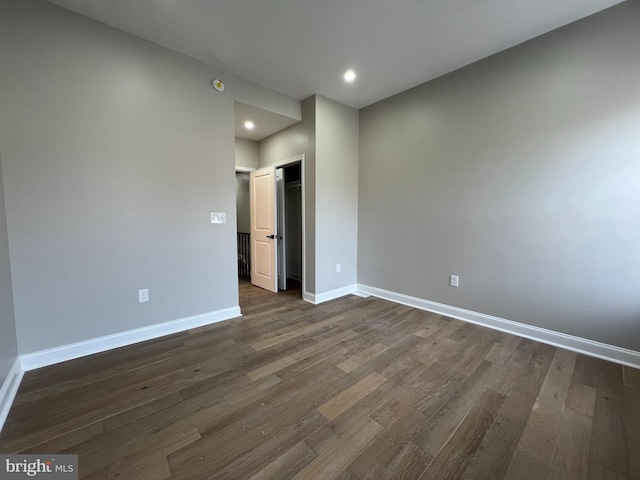 unfurnished room featuring dark wood-type flooring, recessed lighting, and baseboards