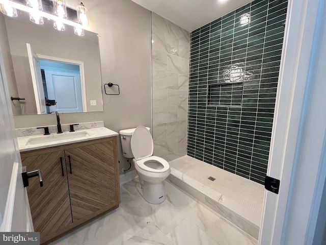 bathroom featuring marble finish floor, toilet, a tile shower, vanity, and baseboards