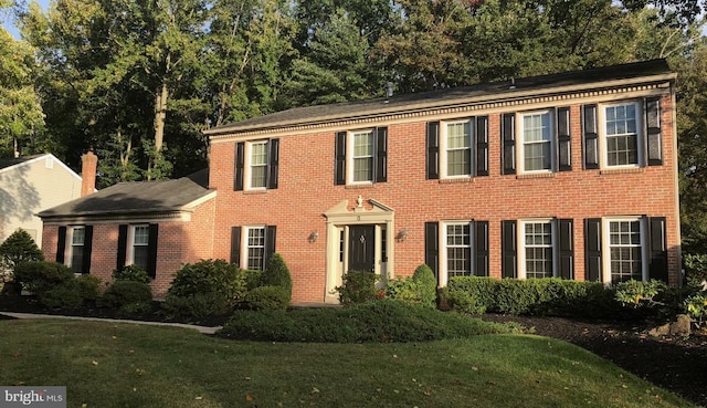 colonial home featuring brick siding and a front lawn