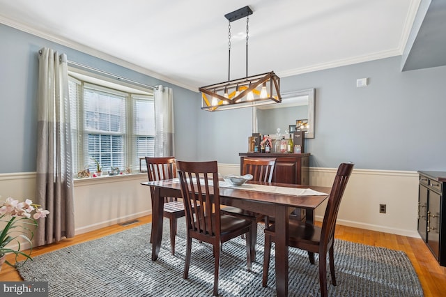 dining space with visible vents, ornamental molding, baseboards, and wood finished floors