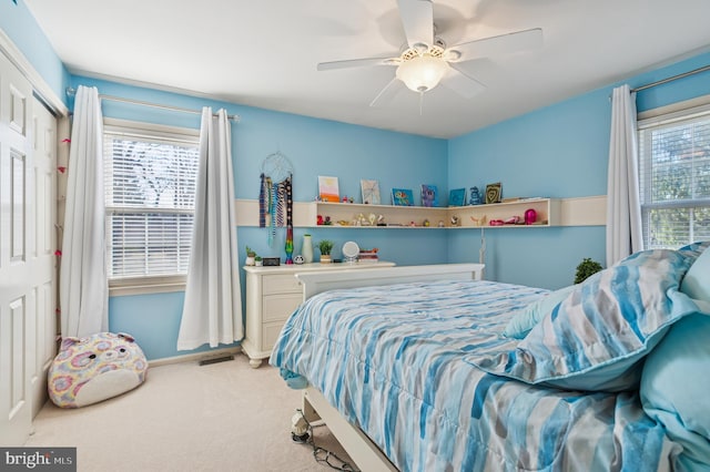 bedroom featuring visible vents, multiple windows, light colored carpet, and a ceiling fan