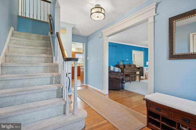 stairway featuring wood finished floors, baseboards, and ornamental molding