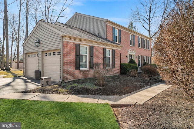 view of home's exterior with an attached garage, brick siding, driveway, and roof with shingles