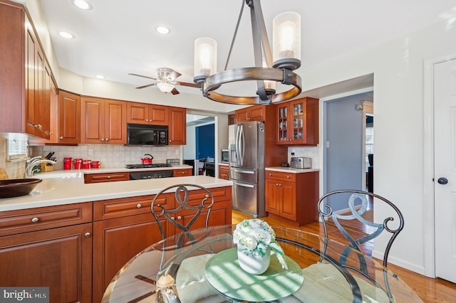 kitchen with light countertops, stainless steel refrigerator with ice dispenser, black microwave, and a sink