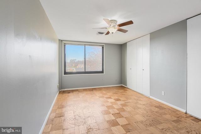 empty room with visible vents, a ceiling fan, and baseboards