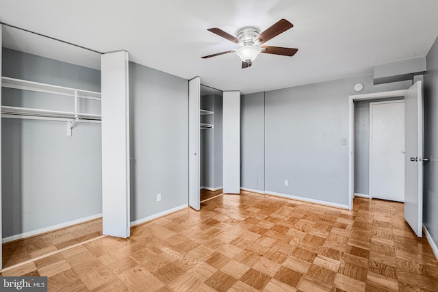 unfurnished bedroom featuring two closets, baseboards, and a ceiling fan