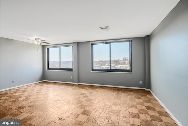 empty room with visible vents, ceiling fan, and baseboards