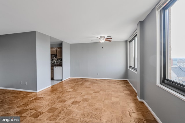 unfurnished room featuring plenty of natural light, baseboards, and ceiling fan