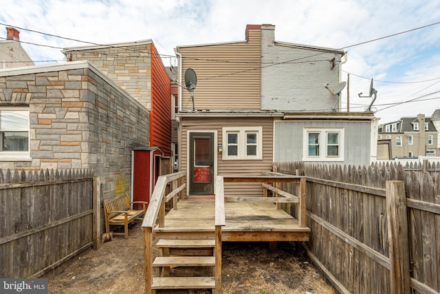 back of property with a deck and fence