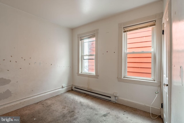 carpeted spare room with a baseboard heating unit and baseboards