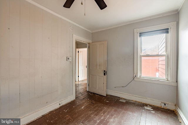 unfurnished room with a ceiling fan, wood-type flooring, crown molding, and baseboards