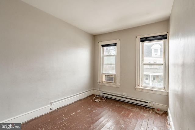 unfurnished room featuring a baseboard heating unit and hardwood / wood-style floors