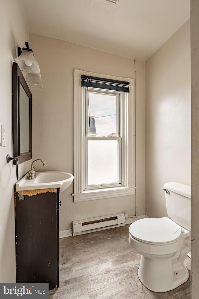 bathroom with a baseboard radiator, vanity, toilet, and wood finished floors