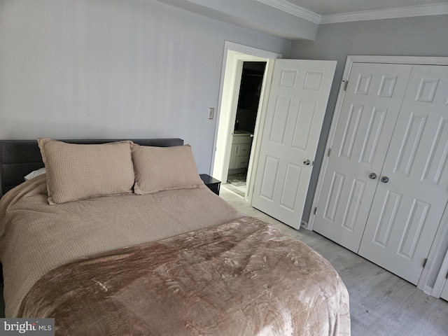 bedroom featuring a closet, light wood-style floors, and crown molding